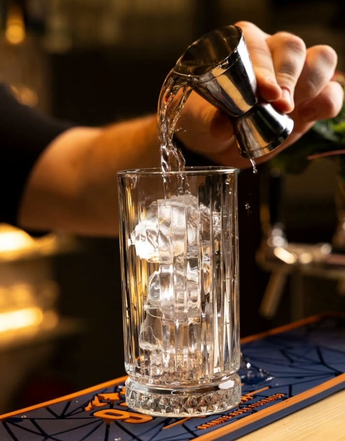 Cocktail wird über Eis eingeschenkt